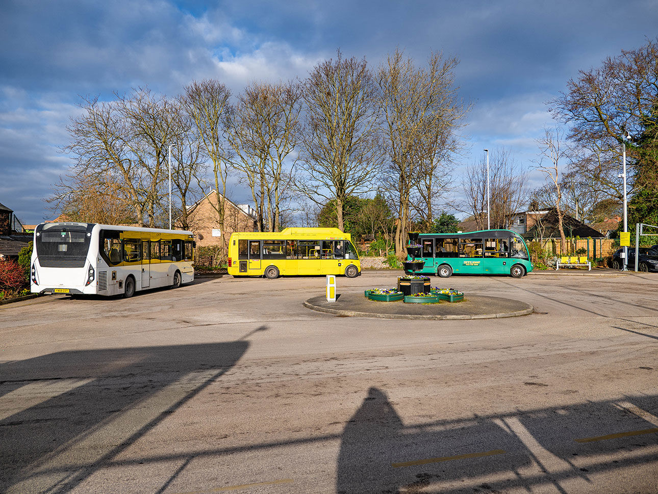 Three buses in a carpark near a roundabout. 