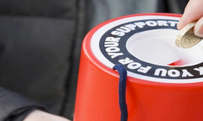 A person putting money in to a charity collection box. 