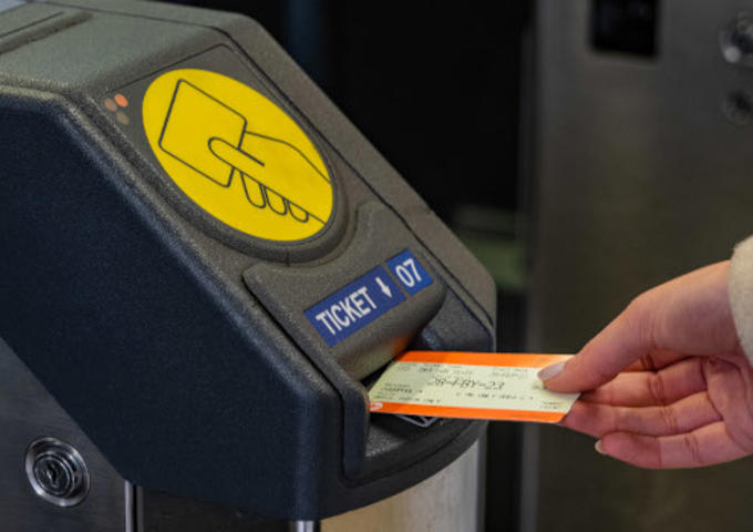 A passenger is inserting their ticket into a barrier to leave or enter a station. 