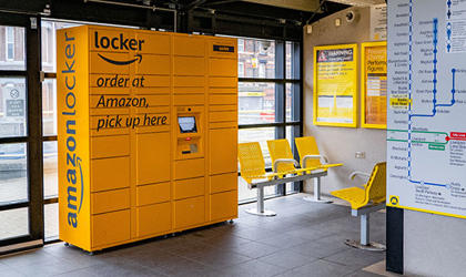 Amazon lockers in a train station. There is seating and information posters. 