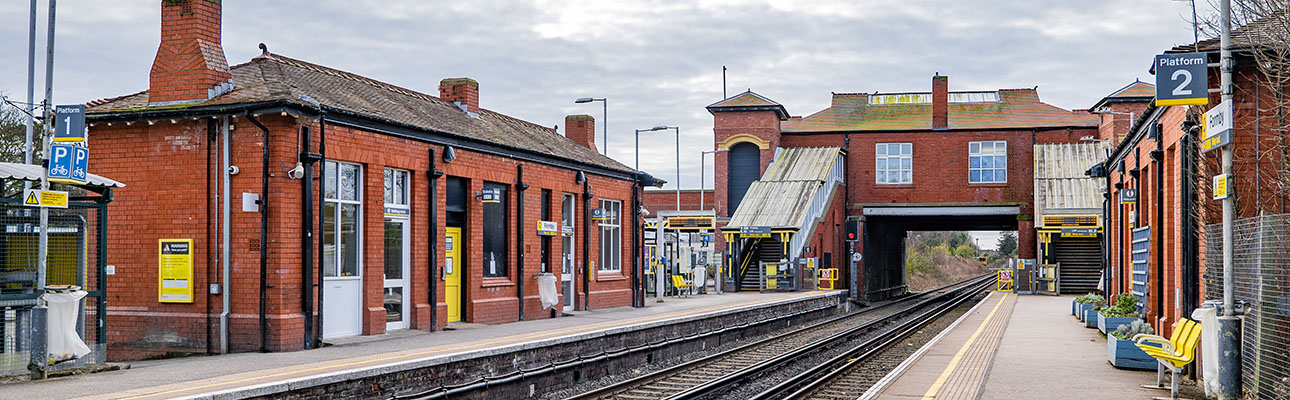 The platform at Formby station. The station buildings and a stairway appear.