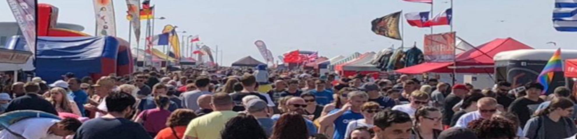 A large crowd looking at the many stalls at New Brighton on a summer day