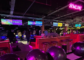 Bowling balls and lanes. It is darkly lit with bright neon signs.