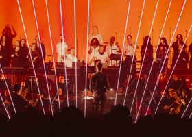 Orchestra on stage with flashing lights at a night time concert