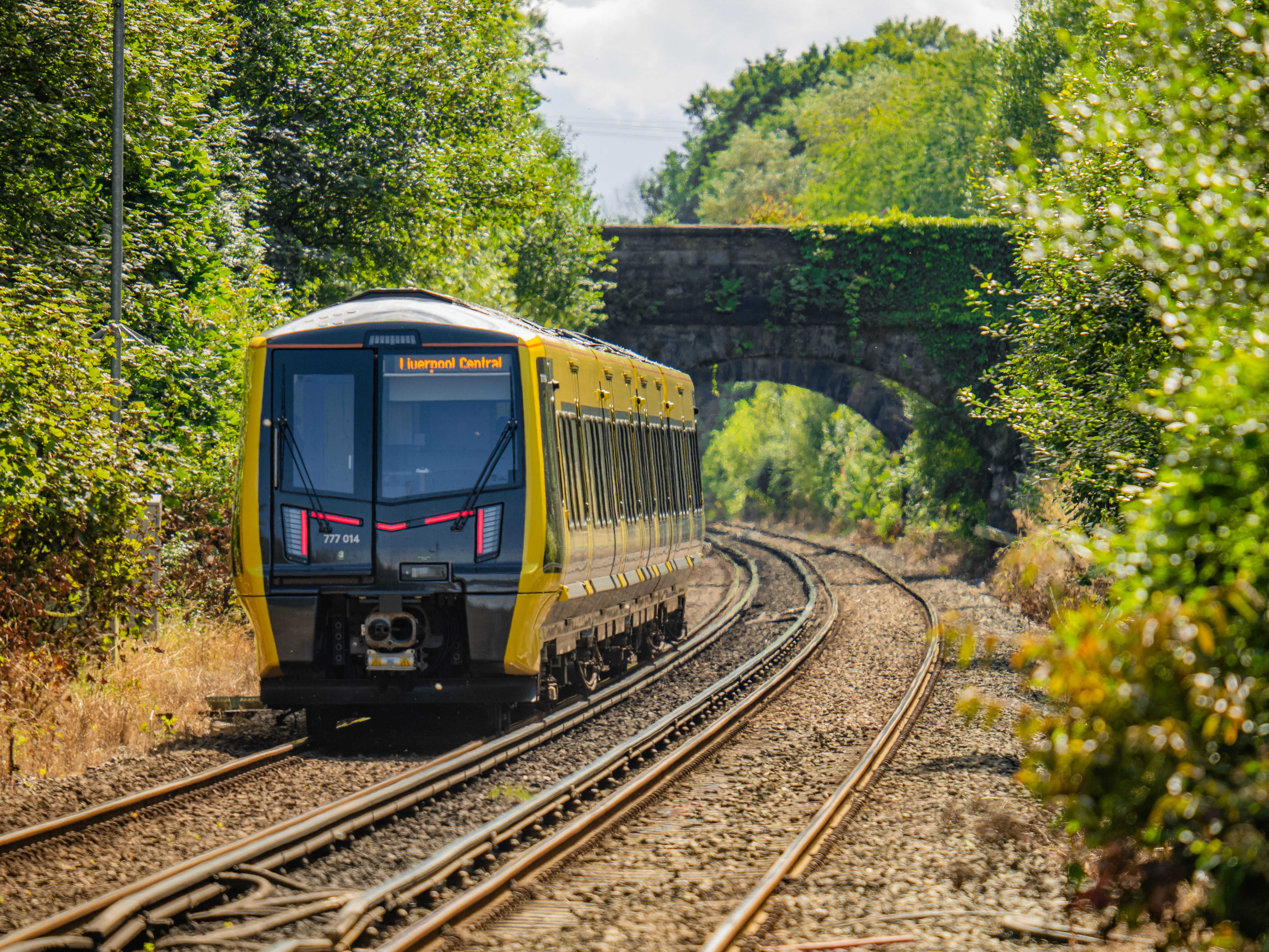 An oncoming 777 train at Aughton Park station at daytime.