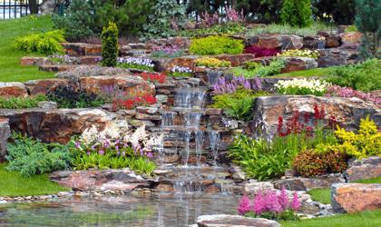 A waterfall outside with brightly coloured flowers.